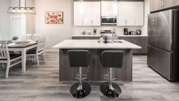 A modern kitchen with white cabinets, stainless steel appliances, and a central island with bar stools.