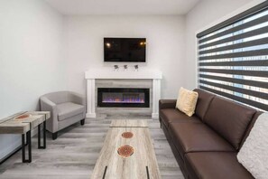 Cozy living room with a fireplace, flat-screen TV, and large window.