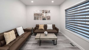 A modern living room with two brown leather sofas, a coffee table, and a wall-mounted art display.