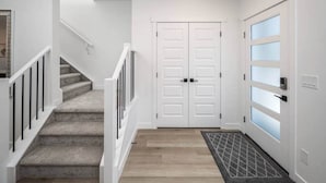 A staircase with a carpeted landing leading to a white door with frosted glass panels.