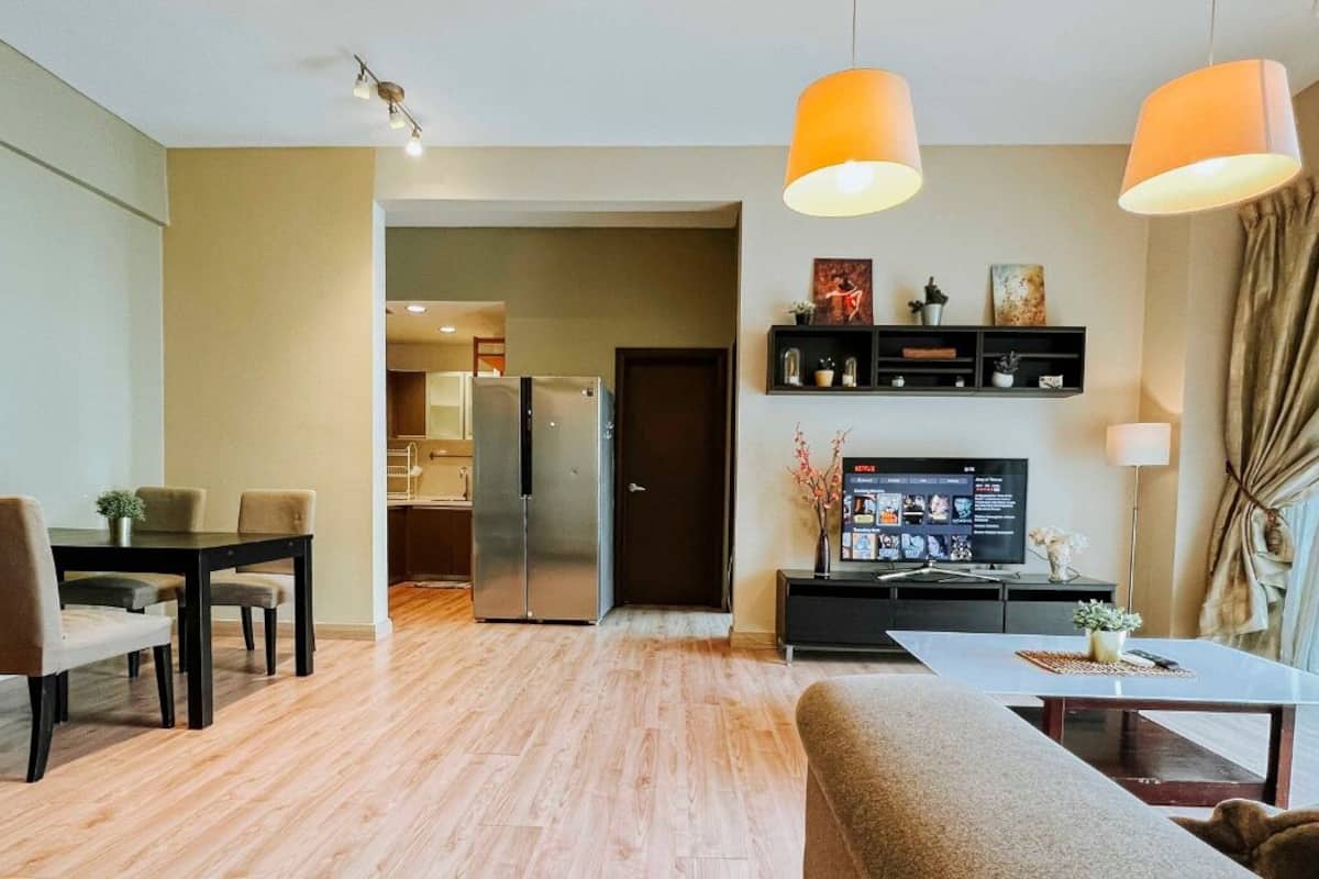Una sala moderna con comedor, una cocina al fondo y un televisor en la pared.