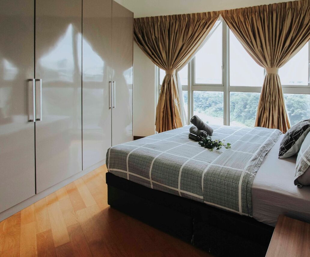 A bedroom with a bed, curtains, a wardrobe, and a window with a view.