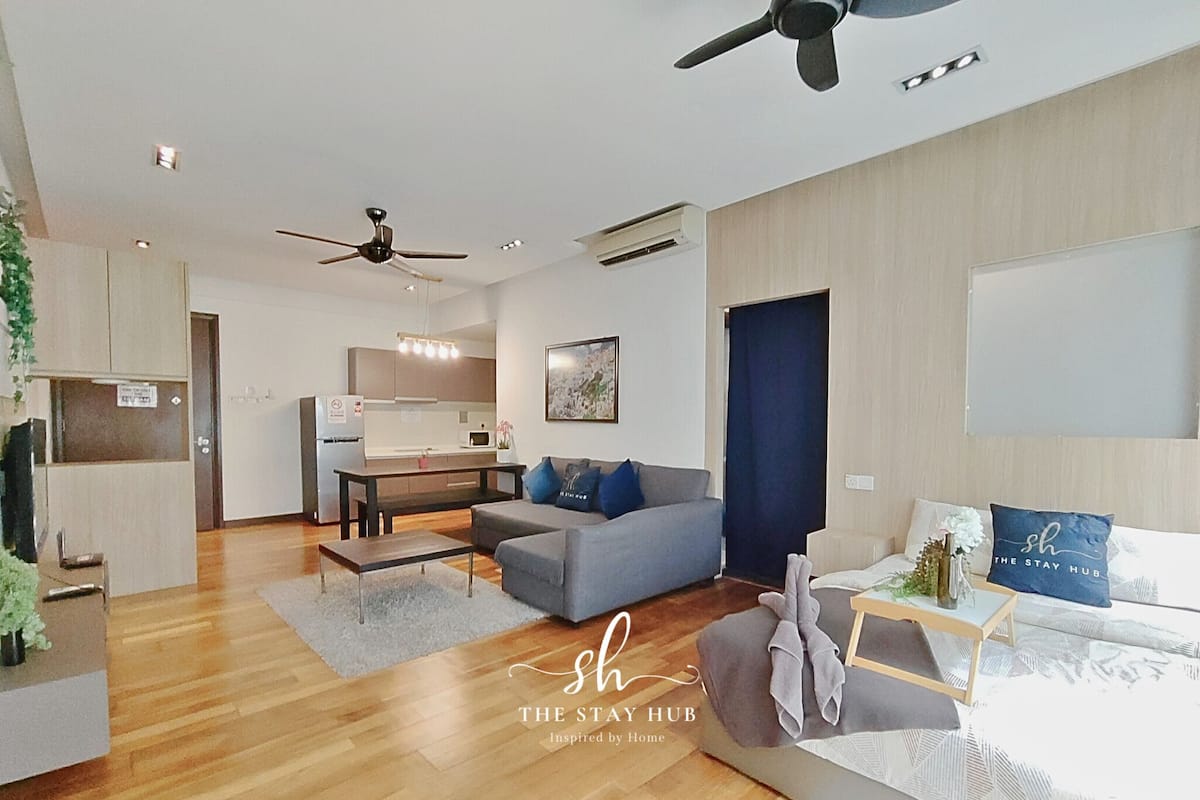Un apartamento moderno con cocina, comedor y sala de estar. Cuenta con ventilador de techo, aire acondicionado y una cama con un almohada que dice 'The Stay Hub'.