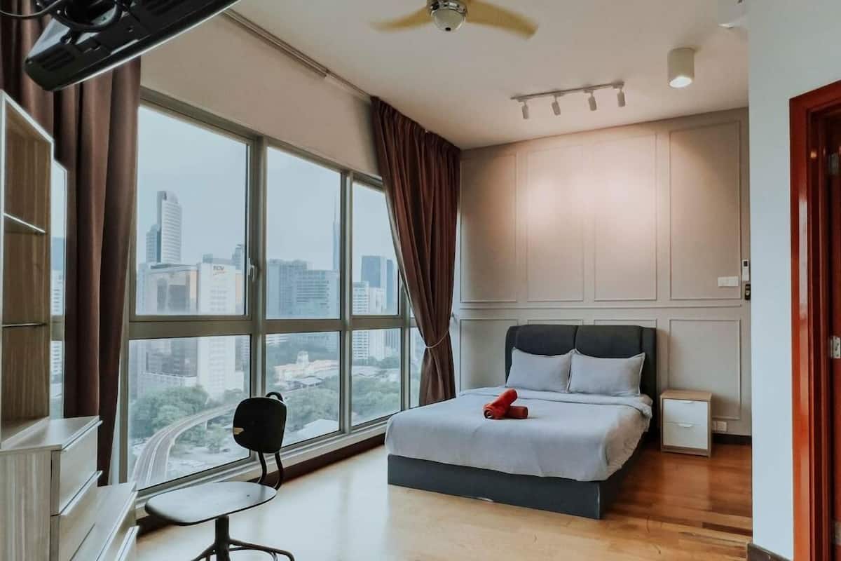 Un dormitorio moderno con un ventanal grande, una cama, un escritorio y una silla.