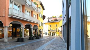 A cobblestone street lined with multi-story buildings, some with balconies and storefronts. - Ruga Vacation Rental 4 in Ascona (Ascona)