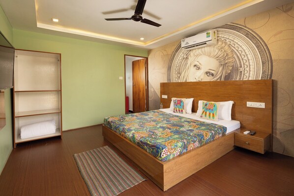 Un dormitorio con una cama de madera, ventilador de techo, aire acondicionado de pared y cabecera estampada.