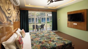 A hotel room with a large bed, a ceiling fan, a TV mounted on the wall, and a view of the outdoor area. - Palolem Casa (Canacona)