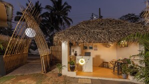 A rustic hut with a thatched roof, a small reception desk, and a few potted plants. - Palolem Casa (Canacona)