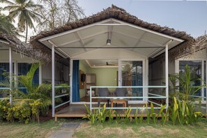 A covered outdoor area with a table and chairs, surrounded by plants and palm trees. - Palolem Casa (Canacona)