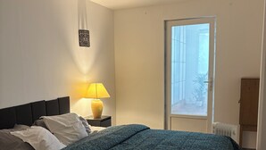 A bedroom with a large bed, a bedside lamp, a window, and a radiator.