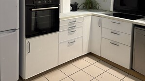 A modern kitchen with white cabinets, a black oven, a microwave, and a stove.