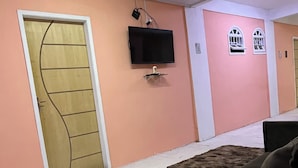 Una habitación con un televisor instalado en la pared, una puerta de diseño peculiar y una alfombra pequeña en el suelo.