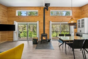 Ein modernes Interieur mit einer holzverkleideten Wand, einem Kamin, einem Essbereich und einer Küche.