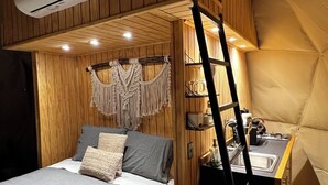 Una habitación acogedora y compacta con literas, una pequeña kitchenette y una zona de descanso tipo tienda de campaña.