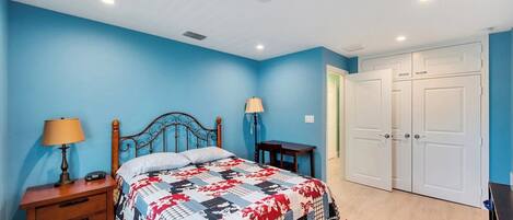 A bedroom with a bed, nightstands, a desk, and a wardrobe.