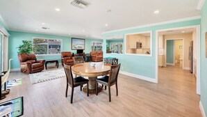 Un salon spacieux avec une table à manger en bois, des canapés en cuir et une grande fenêtre.