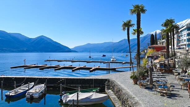 A marina with boats docked, a cobblestone path, and buildings with balconies overlooking the water. - Ruga Vacation Rental 7 in Ascona (Ascona)