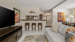 A modern living room with a flat-screen TV, a sofa, a coffee table, and a patterned rug. - Corner Unit 1 Block to Beach in Heart of Waikiki! FREE Parking & Wi-Fi, AC! (Honolulu)