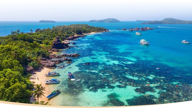 Une zone côtière caractérisée par des eaux turquoise et limpides, des bateaux et une plage de sable.
