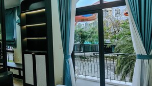 Une chambre d’hôtel avec un lit, un ventilateur de plafond, une fenêtre avec des rideaux et une vue sur l’extérieur.