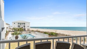 A beachfront hotel with a pool, a beach view, and a balcony with chairs. - Oceanfront Condo w/ Pool, Late Summer Availability (Ocean Isle Beach)