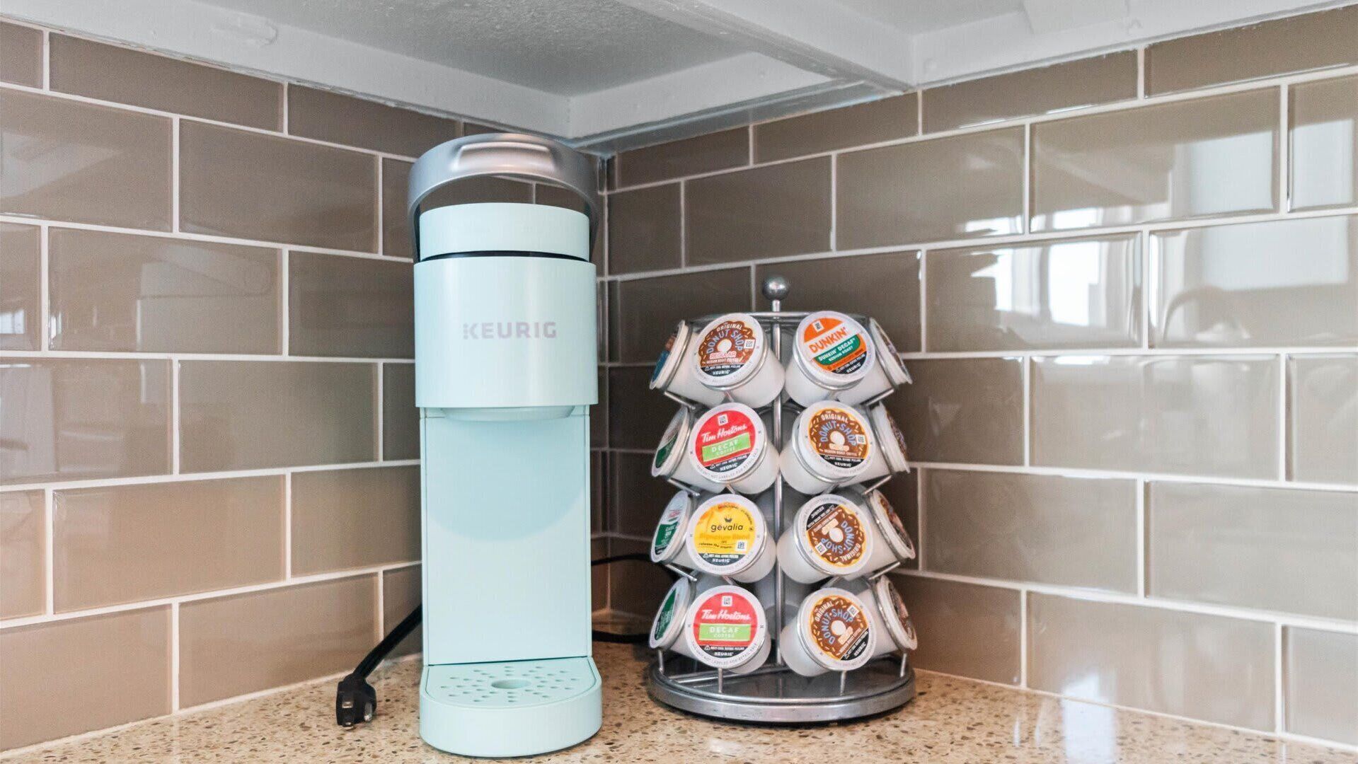 A kitchen with a Keurig coffee maker and a coffee pod holder with various brands.