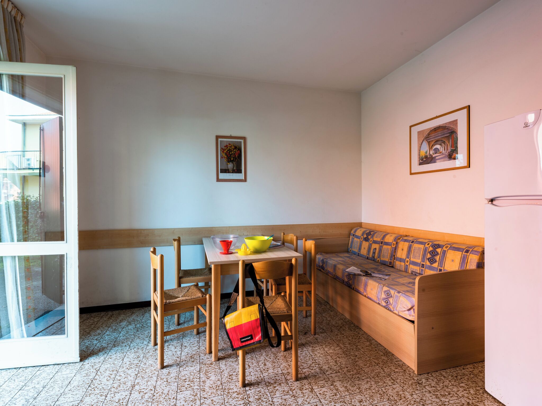 A compact living space with a wooden table, chairs, a sofa, and a refrigerator.