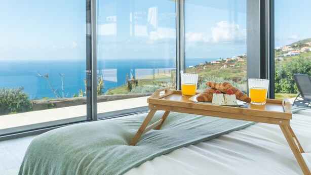 Quarto com uma grande janela com vista para a costa.
