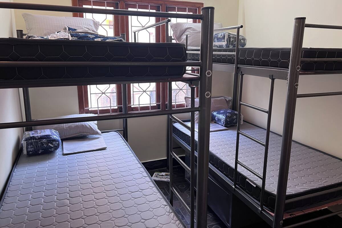 A bunk bed room with a window, a door, and a metal railing.
