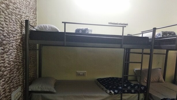 A bunk bed room with a brick wall, a power outlet, and a window. - Soloscape budget friendly backpackers hostel (Bengaluru)
