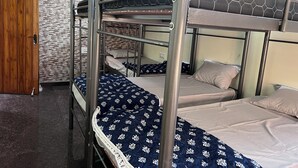 A bunk bed room with a wooden door, a textured wall, and a ceiling light. - Soloscape budget friendly backpackers hostel (Bengaluru)