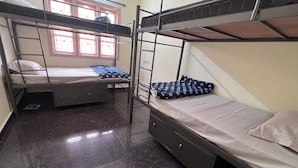 A dormitory room with bunk beds, a window with bars, a small cabinet, and a tiled floor. - Soloscape budget friendly backpackers hostel (Bengaluru)