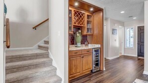 Un escalier mène à une cuisine équipée de meubles en bois et d’un four encastré.