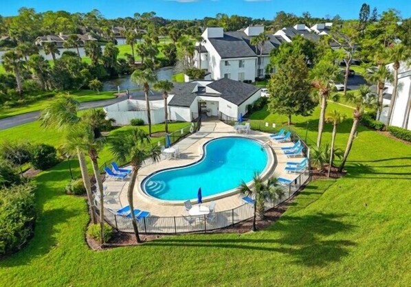A residential area with a swimming pool, surrounded by palm trees and houses. - Fairway Breeze: Sawgrass Golf Course Views | Pool + Beach Access (Ponte Vedra Beach)