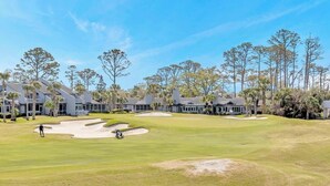 Un parcours de golf doté de bunkers, de palmiers et d’un club-house.