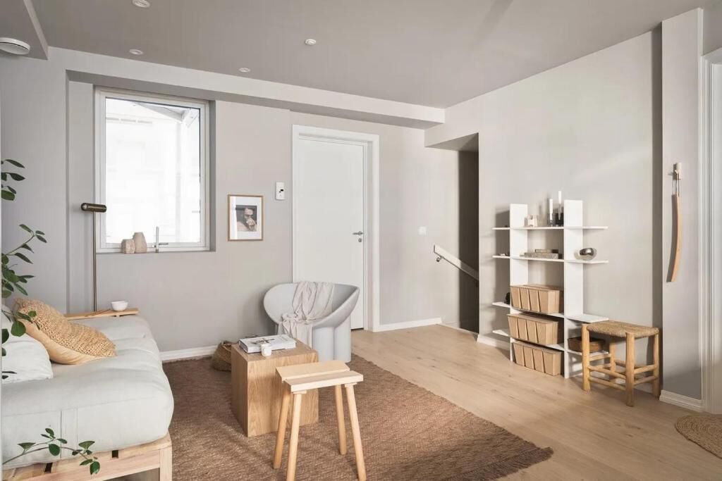 A modern living room with a white sofa, a coffee table, a chair, and a bookshelf.