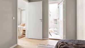 Un dormitori amb un llit, una porta que dona a un balcó i vistes cap a l'exterior.