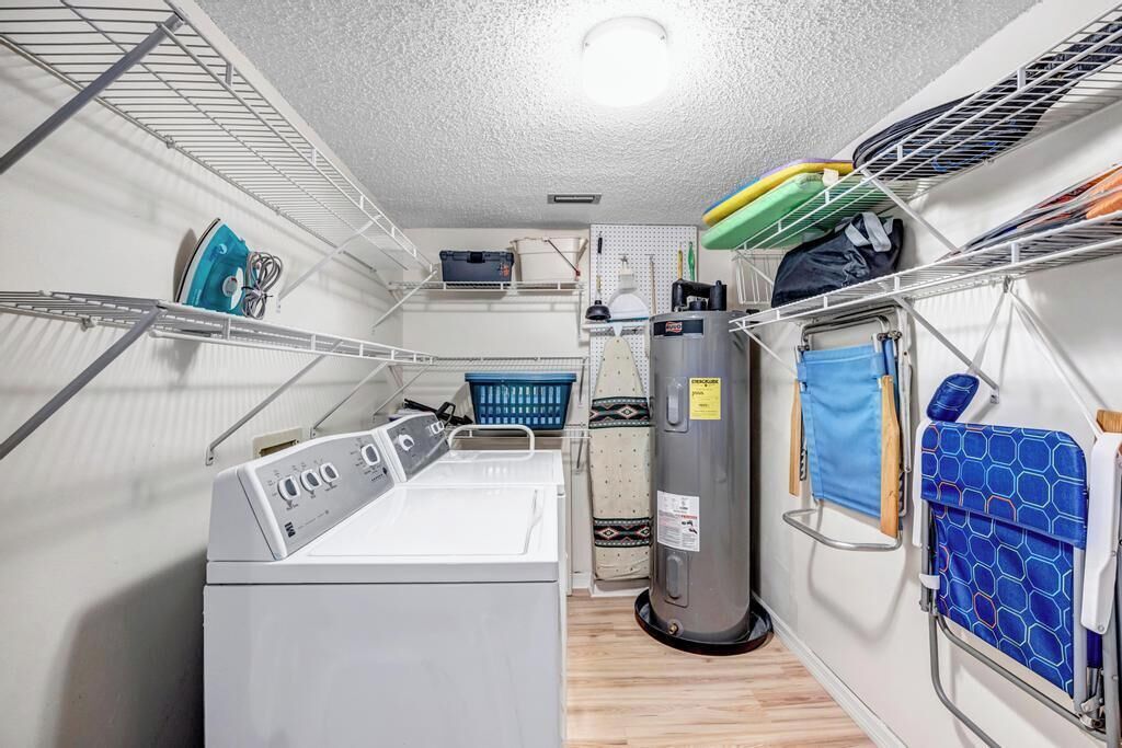 A compact laundry room with a washing machine, a dryer, and shelves for storage.