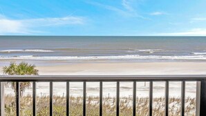 A beach view from a balcony with a railing, sandy beach, and ocean. - Crescent Breeze - Oceanfront w/incredible views, lanai & pool (St. Augustine)