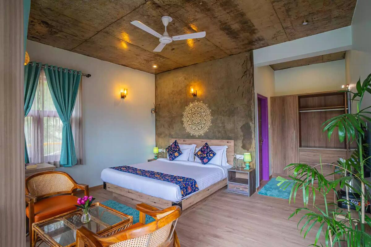 A bedroom with a bed, a ceiling fan, a wall tapestry, and a wooden wardrobe.