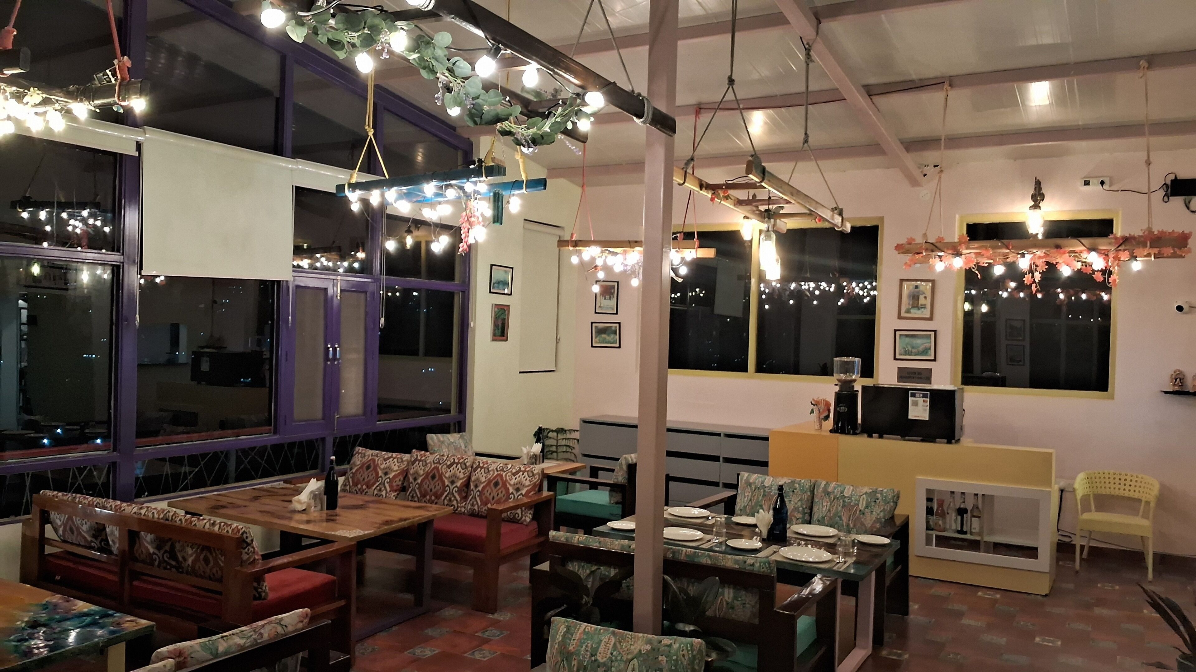 Un restaurante acogedor con muebles de madera, ventanas amplias y luces colgantes.