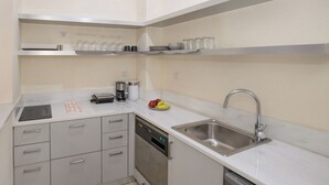 A modern kitchen with a stainless steel sink, a coffee maker, and a dish rack.