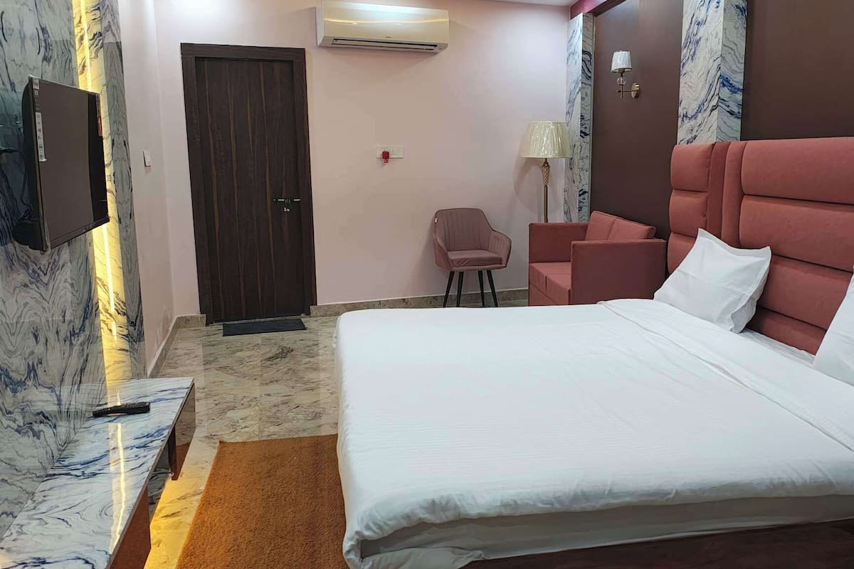 A bedroom with a large bed, a desk, a chair, and a wardrobe.