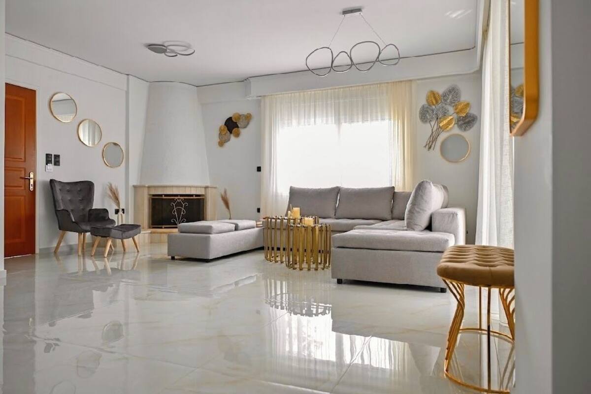 Una sala de estar moderna con un sofá gris, un sillón negro, una mesa de centro redonda y una chimenea.