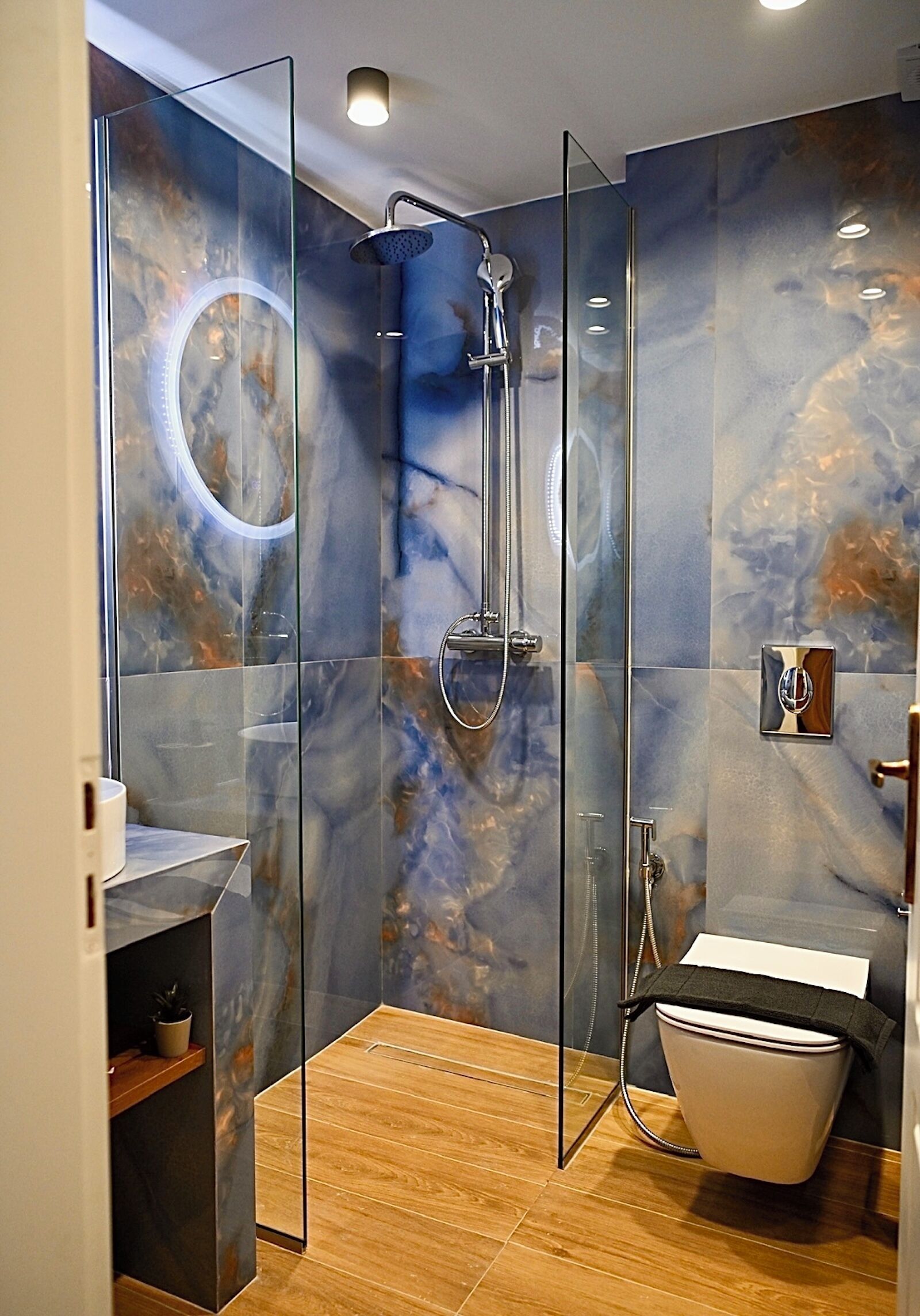 Un baño moderno con ducha de vidrio, bañera independiente y paredes con diseño de mármol.