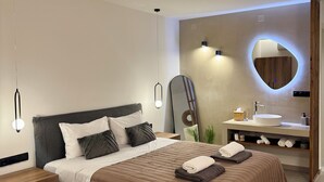 Een moderne slaapkamer met een groot bed, nachtkastjes, een kaptafel met spiegel en een wandlamp.