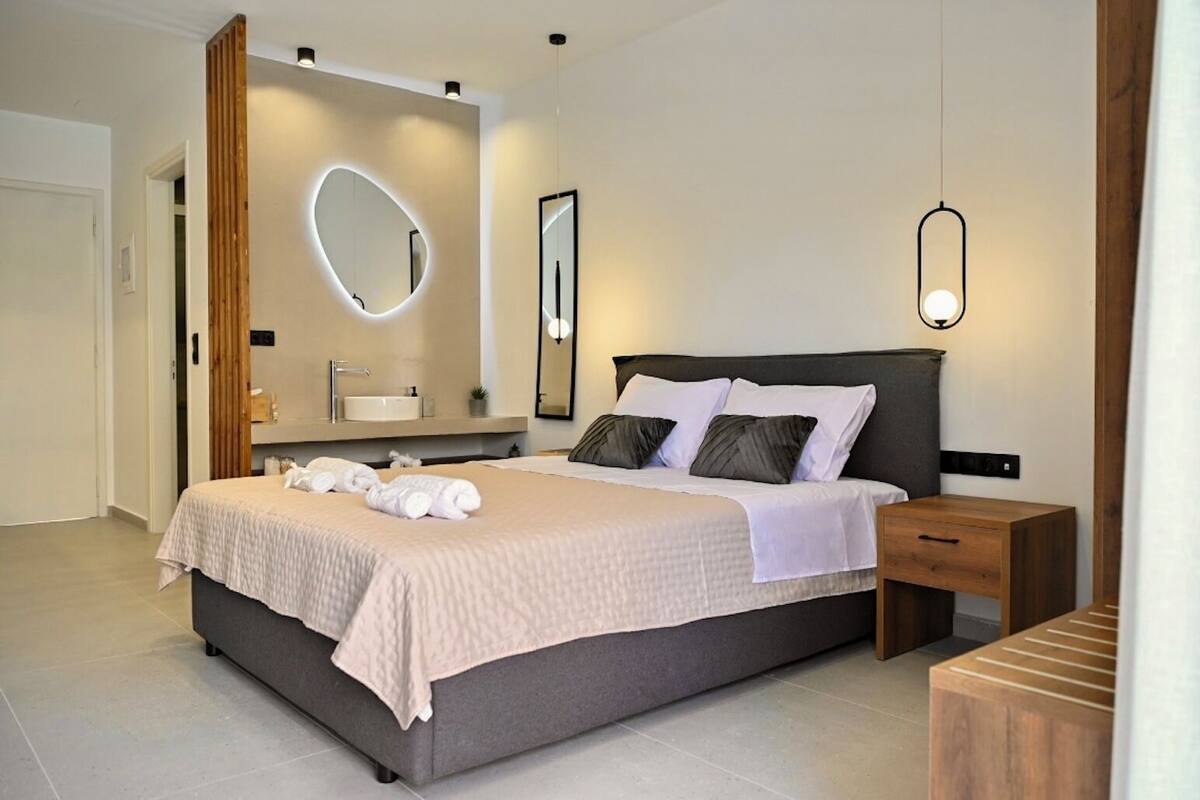 Un dormitorio moderno con una cama grande, mesitas de noche, tocador empotrado y un espejo.