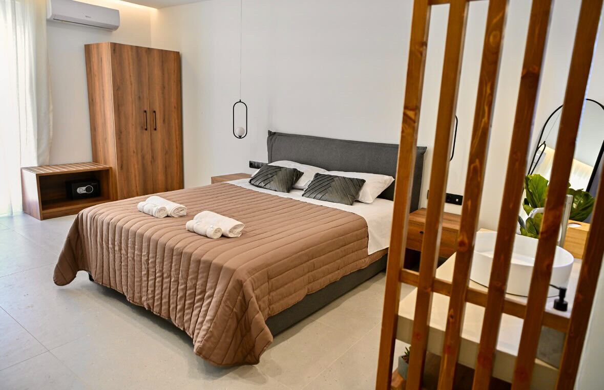 Een moderne slaapkamer met een groot bed, een kledingkast, een nachtkastje en een plant.
