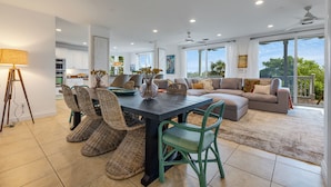 A spacious living area with a dining table, wicker chairs, a sofa, and a view of the outdoors. - SEVENTH HEAVEN~Waterfront 5 BR, 4 Ba Townhome with Pool, Elevator & Dockage! (Key West)