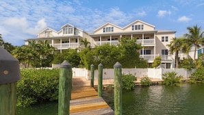 A wooden pier leading to a waterfront property with multiple balconies and a white picket fence. - SEVENTH HEAVEN~Waterfront 5 BR, 4 Ba Townhome with Pool, Elevator & Dockage! (Key West)